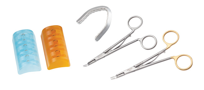 Assorted medical tools: two dental impression trays, a mouth retractor, and two surgical forceps with gold and silver handles.