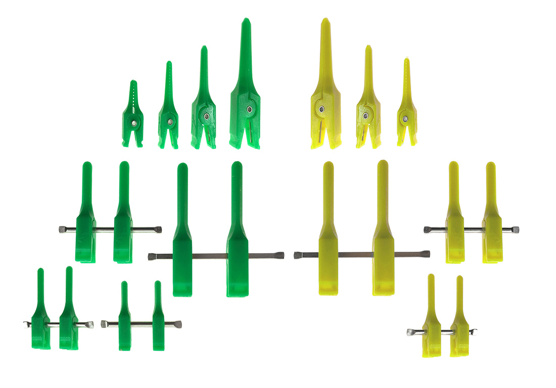 A collection of green and yellow plastic clip-like tools arranged in rows.